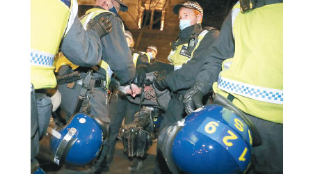倫敦警員拘捕涉違限制措施的示威者。（美聯社圖片）
