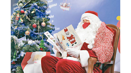 打扮聖誕老人的郵局職員閱讀小朋友寄來的信件。（美聯社圖片）