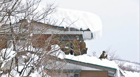 有建築物屋頂堆起厚厚積雪，自衞隊協助剷雪。