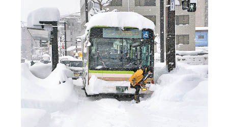 巴士在厚厚積雪中動彈不得。（美聯社圖片）