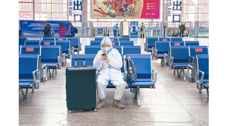 有人穿上保護衣在乘客稀少的北京南站候車。（美聯社圖片）