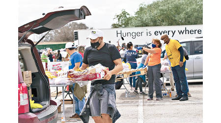德州休斯敦食物銀行職員搬運食物上車，再派予有需要人士。（美聯社圖片）