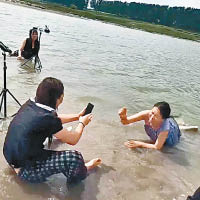 網絡主播在水深較淺的河岸濕身拍攝。