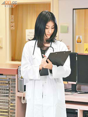 穿上醫生袍的陳慧琳拿着病歷細閱，似模似樣。