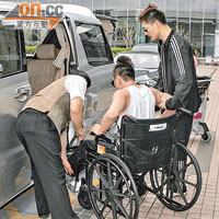 坐輪椅的梁漢文要由人扶着上車。