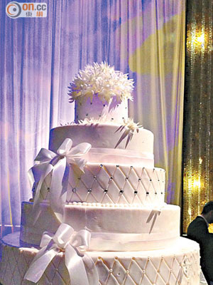 結婚蛋糕高五層，頂層放上白色花裝飾點綴，白色絲帶圍邊。
