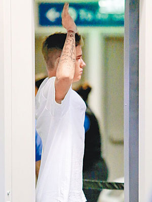 Justin舉高雙手讓海關檢查時，褲子卻因太鬆掉下。（東方IC圖片）