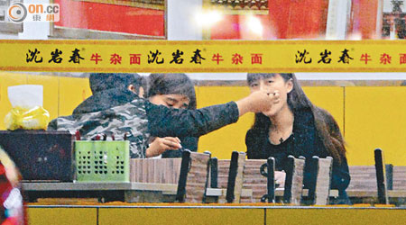 陳浩民隔着助手向女子餵食牛肉。