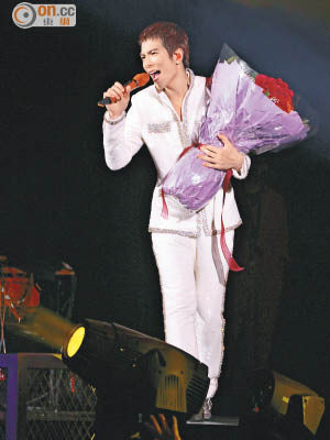 一身白馬王子閃look的蕭敬騰，拿着大束紅玫瑰演唱。