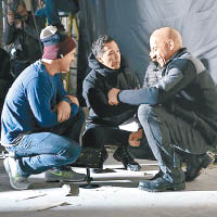 甄子丹在片場與導演及雲狄素（右）蹲在地上交談。