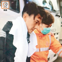 王浩信在救護員陪同下上救護車。