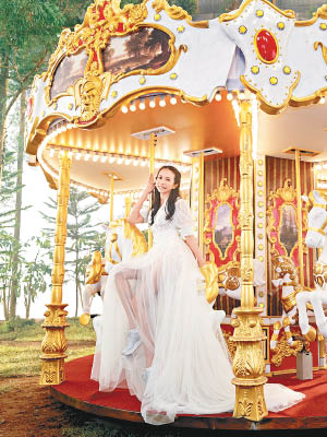 穿紗裙的莫文蔚在新曲MV坐在旋轉木馬上。