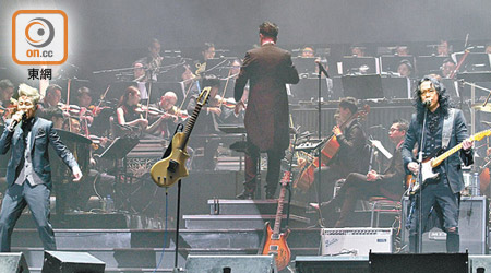 鄧建明（右）彈着結他，在管弦樂團伴奏下演出。