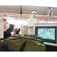 機上有全副裝備人員檢查旅客的健康狀況。