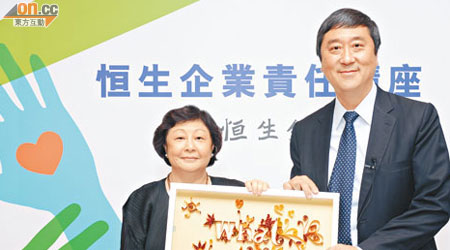 李慧敏（左）向沈祖堯贈送由恒生義工製作的「千金難買」捲紙畫。