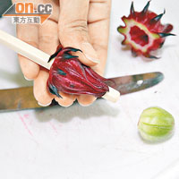 將新鮮採摘的洛神花萼果，切掉頭尾，再用筷子把綠色的果實除走。