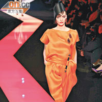 Satin鮮橙色連身裙以「卷軸」凸顯腰身設計，這個「卷軸」亦是系列的設計亮點，它飾於領口、胸口、腰位、膊位，變化多端。