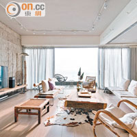 客廳連接露台，可盡覽室外的藍天碧海，配合粗獷的水泥牆身與溫暖的木系家具，令整個空間洋溢自然美。