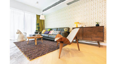 地面鋪設木紋地板，配襯多件木傢俬，加上選用綠色窗簾，頓時令客廳散發出一抹自然色彩。