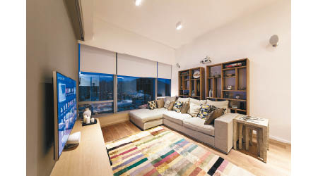 客廳以白和灰作為主色，地板及家具均採用木材來打造，整體配搭簡約自然。色彩繽紛的地氈則豐富了視覺效果。