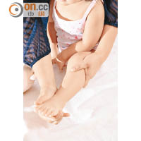 Step 1：<br>一手托穩寶寶，另一手則由寶寶大腿按摩至足部，力度如「擠牛奶」般溫柔。