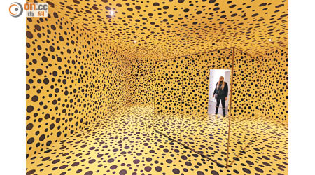 黃底黑點的房間內放了一個以鏡作牆的立方體，拍攝者只要站在某個盲點，就可避開自己並從鏡中拍到門外的人。