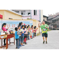 選手們跑經梅林村的小學大門，獲一班學生們為他們加油打氣，氣氛溫馨。