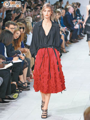 黑色低V上衣是鬆身剪裁，下身的紅色傘裙布滿同色的花卉，對比感強烈。