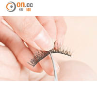 把假睫毛一剪為二，取較長的後半部分，緊貼在眼尾上睫毛的根部黏上便可。