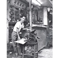 圖中的錦波員工正在使用活字印刷機，逐張紙印刷。