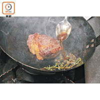用匙羹將油舀到牛扒上，令它受熱平均並吸收香料的味道。