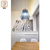飯廳餐枱由白色枱腳配木色枱面，襯以幾何圖案吊燈與斑馬紋掛畫，別具特色。