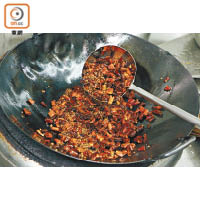 3. 燒熱剩下的菜籽油，轉中火，下青紅花椒和辣椒乾炒至出味，快速撞入大鍋中即成。