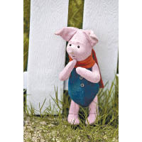 小豬表面是粉紅色毛絨布料，穿上藍色衣服和紅色頸巾。
