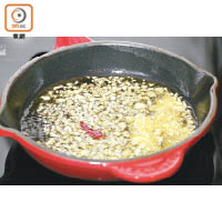 2.用中火煮滾橄欖油，爆香蒜頭和辣椒。