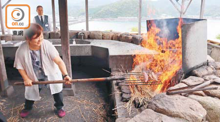 鰹魚半敲燒體驗要拿起重十多公斤的鐵架，把鰹魚肉放上熊熊稻草火堆上燒，一點也不輕鬆。