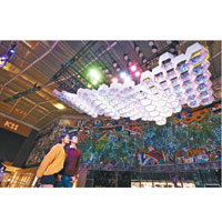 露天廣場中心自天花懸垂着一件如雲的10米長白色藝術裝置，流動的形態是收集香港近十年雨量數據轉化而成的形狀，其燈光裝飾會根據雨量編程而閃動，幻化成一道道彩虹光，猶如彩虹雨。