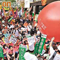 遊行人士在政府總部踢走代表裁員、減薪的氣球。	（黃仲民攝）