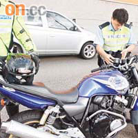 警員查看肇事電單車，並檢走事主的頭盔。	（吳子豪攝）
