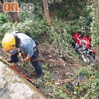 墮山電單車被大樹擱着，消防員游繩落山救援。