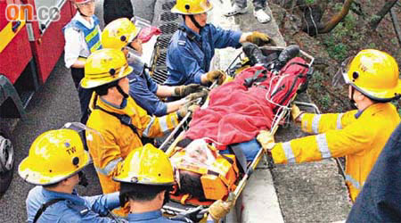 消防員將滾落斜坡受傷的工人救起。	（曾志恒攝）