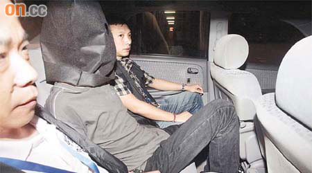 探員將其中一名男犯人蒙頭帶往西九龍警署總部。