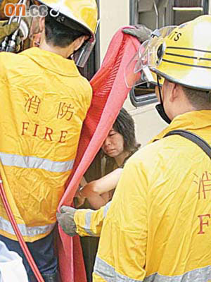 消防員用毛氈遮擋婦人身體，以便剪斷扶手施救。	（林振華攝）