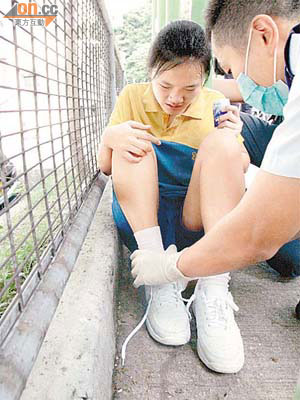 女生坐於路邊接受救護員包紮。	（冼耀華攝）