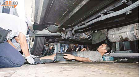 修車工人被壓斷腳骨，躺在車底接受救護員急救。	（蘇仲賢攝）