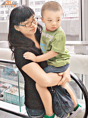 被電梯夾傷手指的男童由母親抱着送院治療。	（左錦鴻攝）