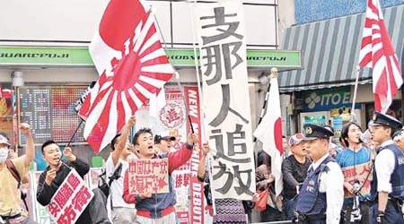 日本右翼團體成員手持日本國旗及標語示威，辱罵中國人。	（互聯網圖片）