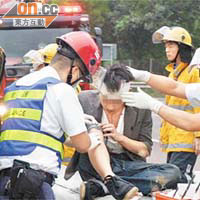 肇事客貨車司機頭部受傷，坐在路邊接受急救。