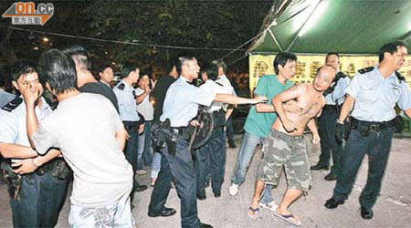 警方拘捕一名紋身男子（右前二）。而持警棍、盾牌警員在場戒備，大批民眾在場圍觀。	（王偉安攝）