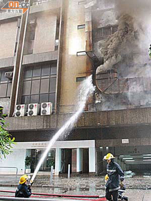 消防員向正在冒煙的大廈外牆油煙槽射水。	（黃君堡攝）